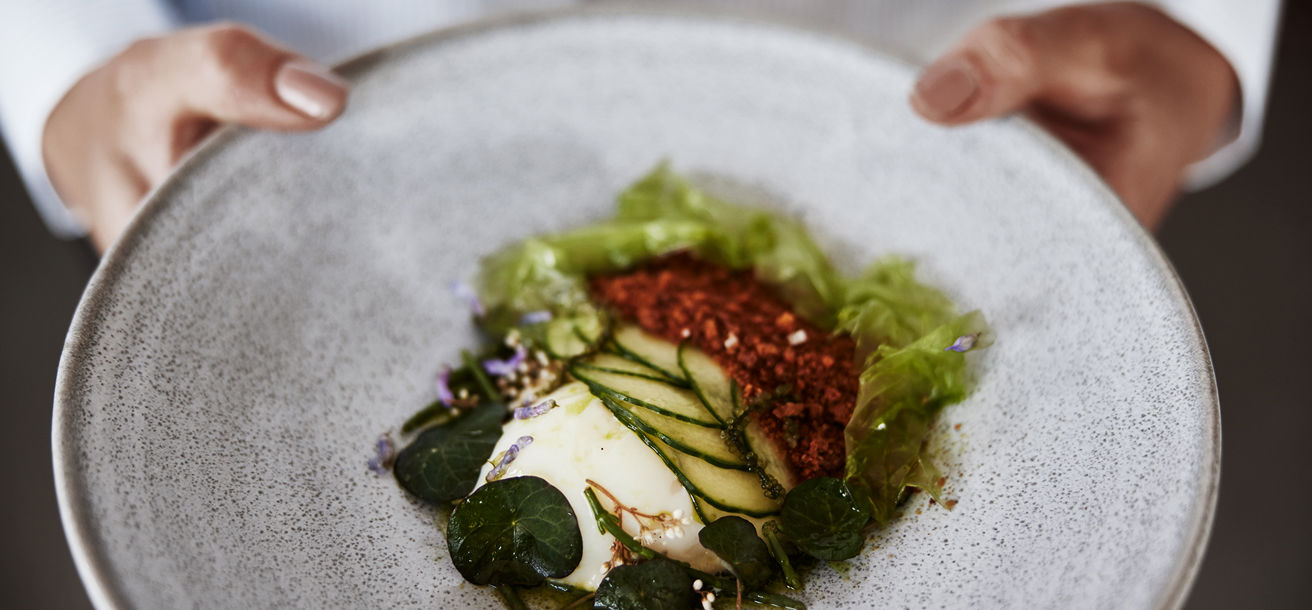 En servitör håller i en tallrik med en maträtt