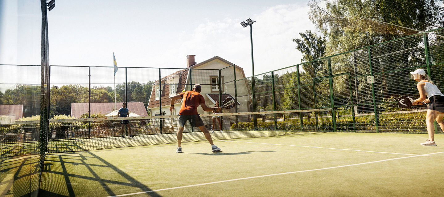 Spela padel på två padelbanor omgivna av grönskande miljöer på Smådalarö