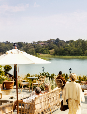 Personer njuter i solen på uteplatsen med utsikt över Hemviken