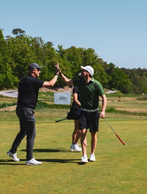 Människor gör high five på golfbana i skärgården