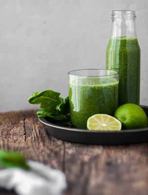 Grön och nyttig smoothie i ett glas och flaska