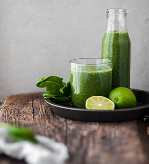 Grön och nyttig smoothie i ett glas och flaska