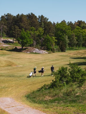 Tre personer på en golfbana