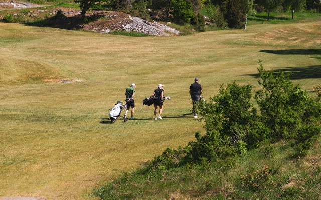 Tre personer på en golfbana