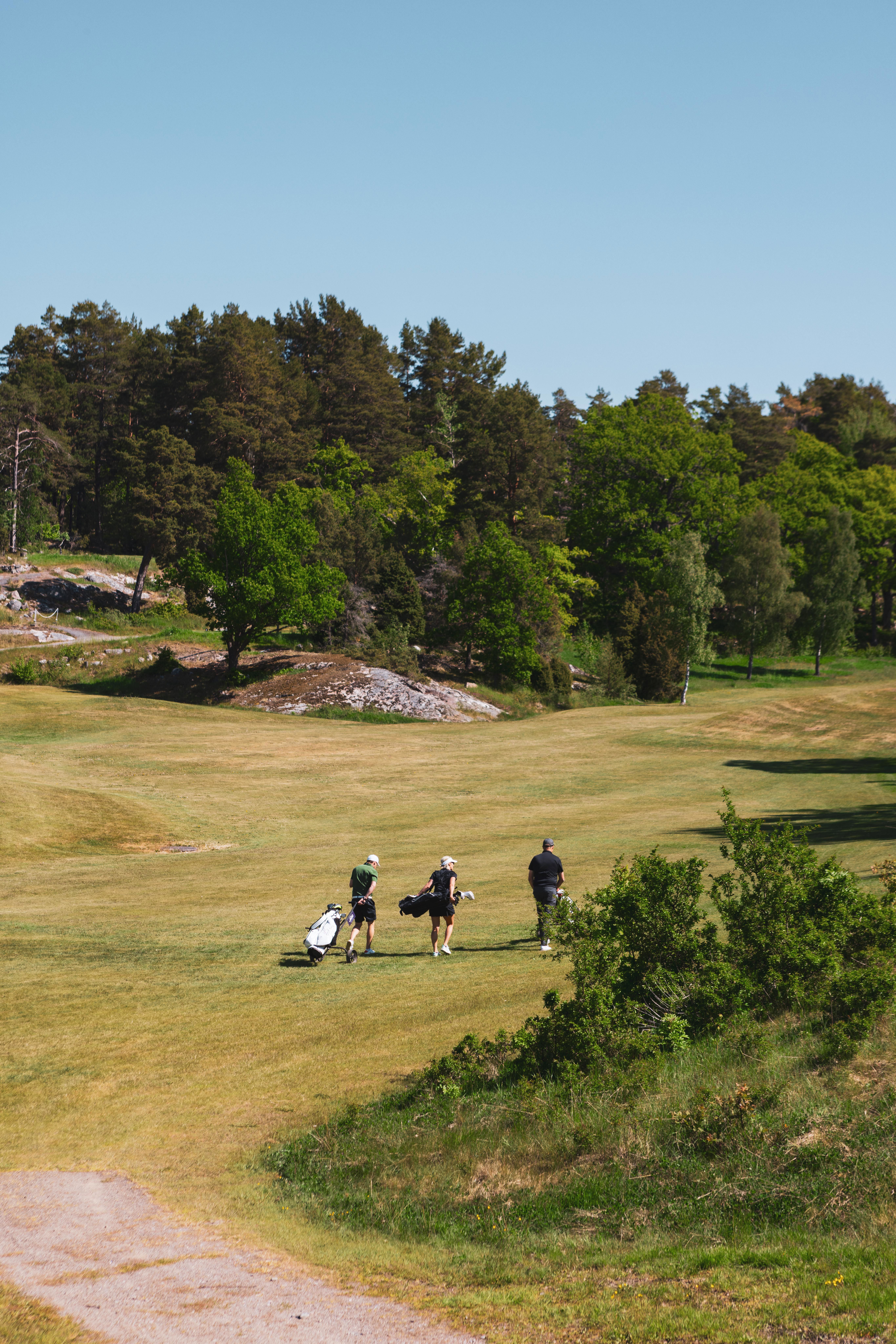 Tre personer på en golfbana
