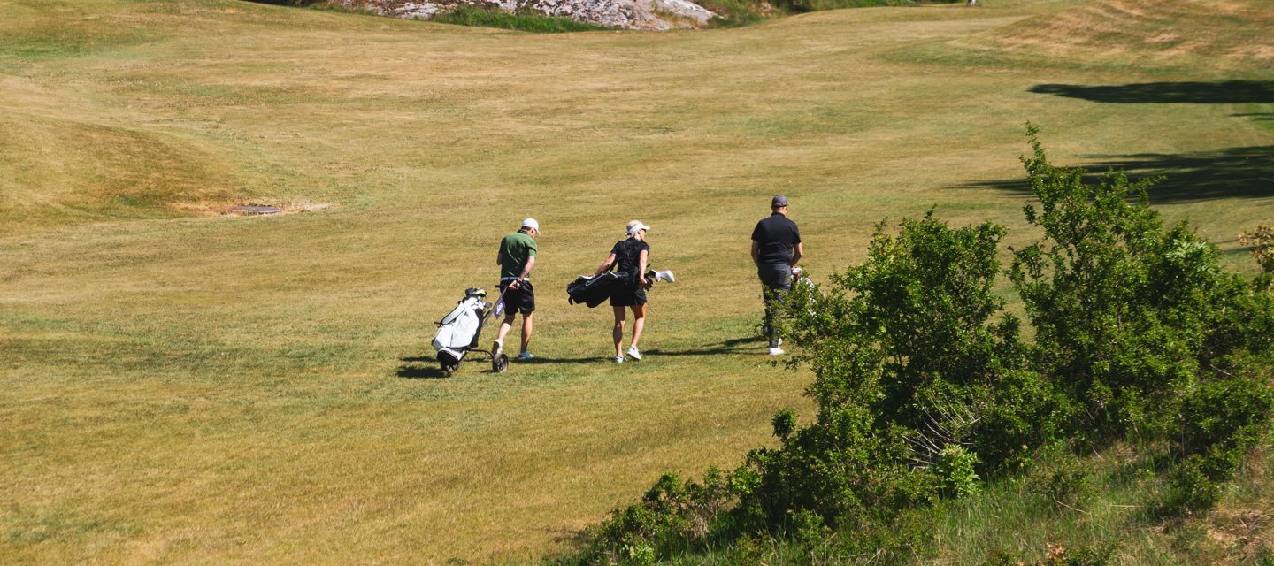 Tre personer på en golfbana