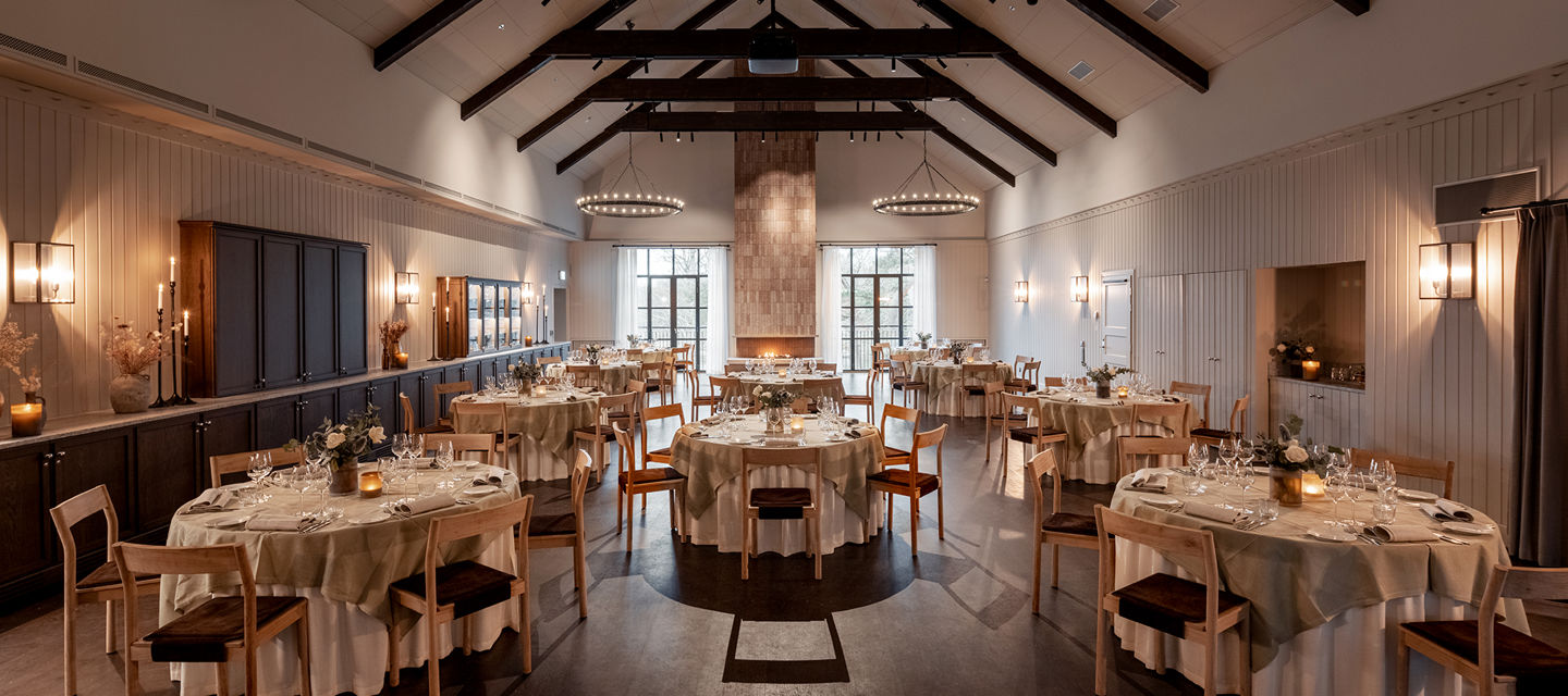 Fest och konferenslokal som är möblerad med runda dukade bord, lokalen har högt i tak