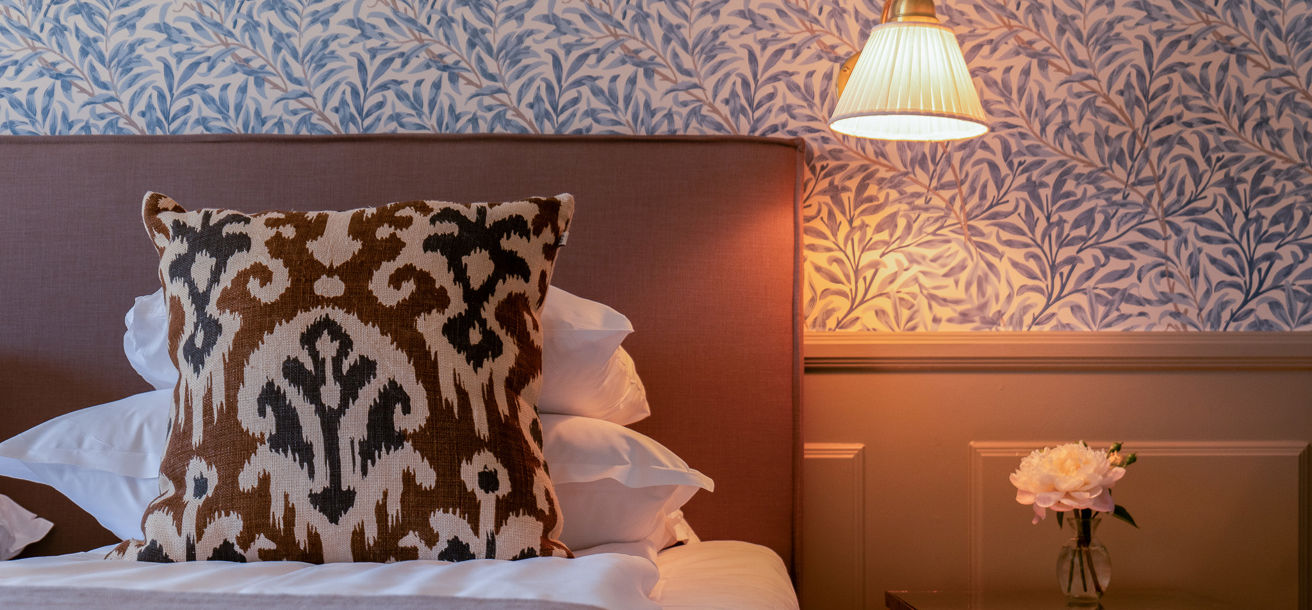 Hotellrum med blåmönstrad tapet och ljusa sobra färger