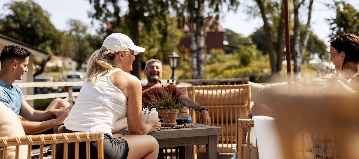 En grupp människor sitter och njuter i solen på uteserveringen