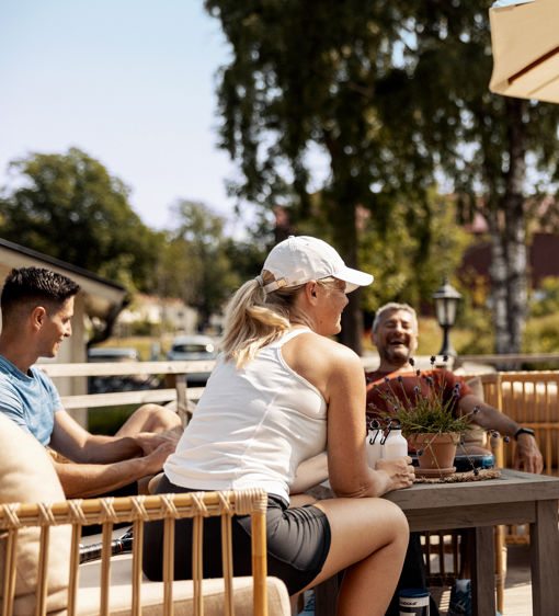 En grupp människor sitter och njuter i solen på uteserveringen