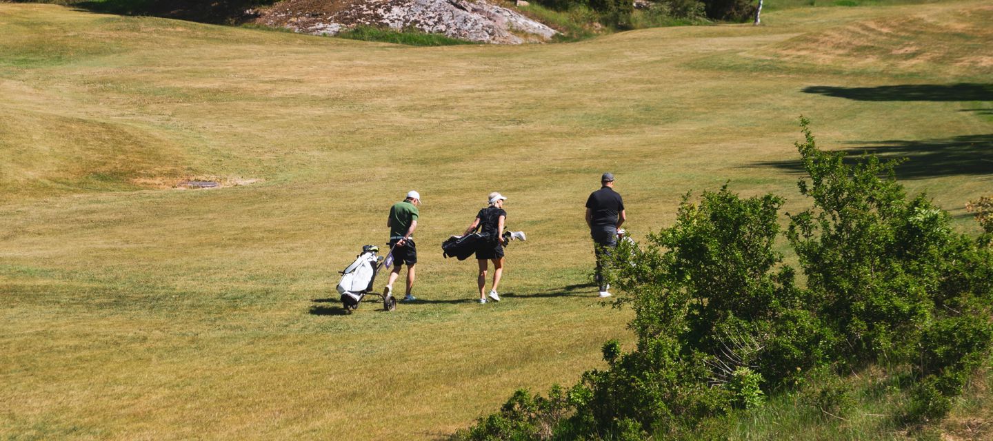 Tre personer på en golfbana