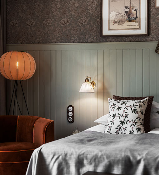 Vackert hotellrum i sobra naturfärger  och mönstrade prydnadskuddar på sängen