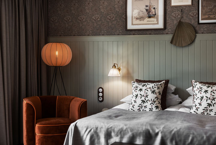 Vackert hotellrum i sobra naturfärger  och mönstrade prydnadskuddar på sängen