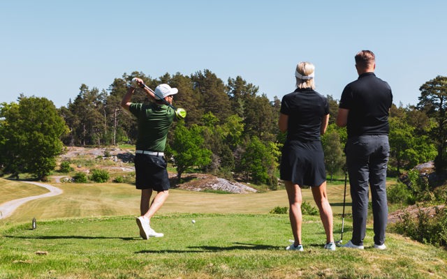 Tre personer på en golfbana