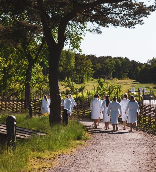 Grupp människor går i badrock mot havet