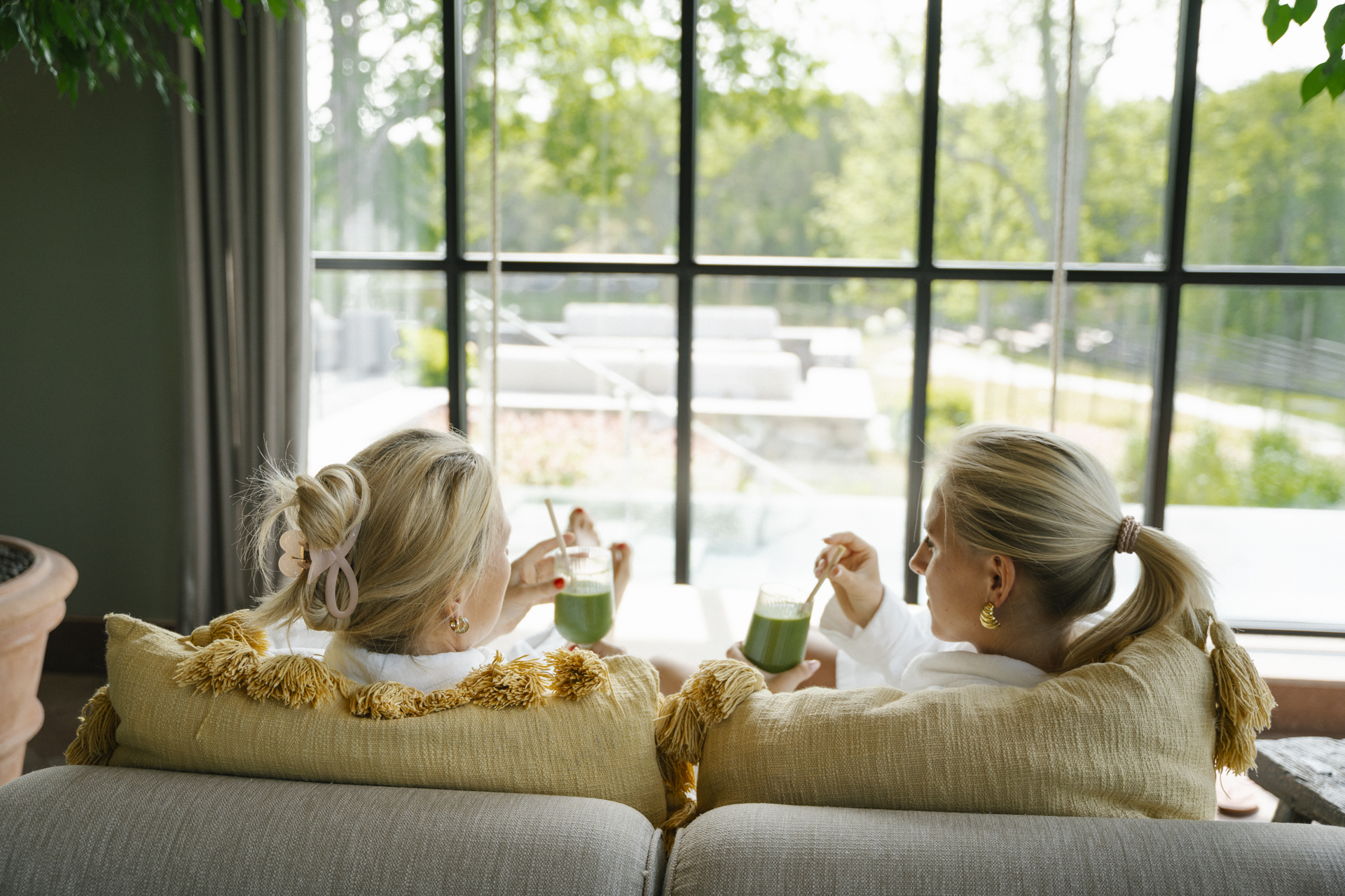 Två kvinnor dricker juice i morgonrockar på spat