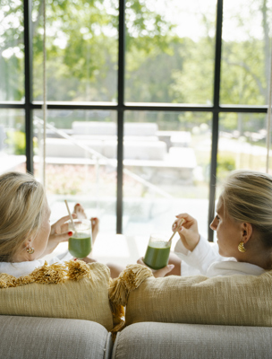 Två kvinnor dricker juice i morgonrockar på spat